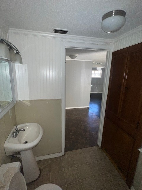 bathroom featuring a textured ceiling, tile patterned floors, and crown molding