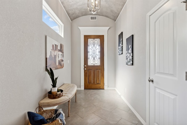 doorway to outside with light tile patterned flooring and an inviting chandelier