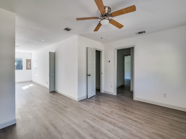 unfurnished room with light hardwood / wood-style floors, electric panel, and ceiling fan