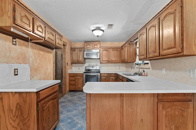 kitchen with sink, stainless steel appliances, kitchen peninsula, and a textured ceiling