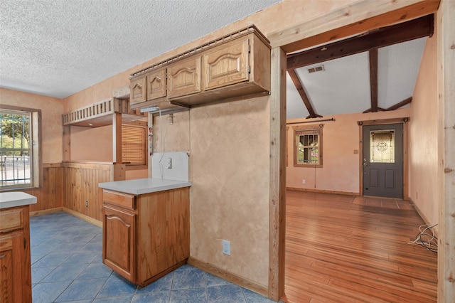 kitchen featuring lofted ceiling with beams, a textured ceiling, and hardwood / wood-style flooring