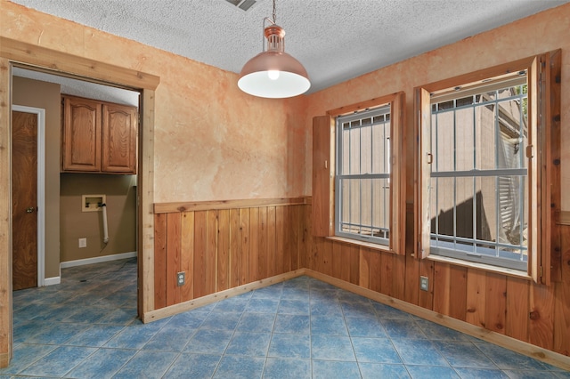 empty room with a textured ceiling and wooden walls