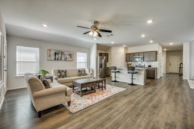 living room featuring ceiling fan, dark hardwood / wood-style flooring, and a healthy amount of sunlight