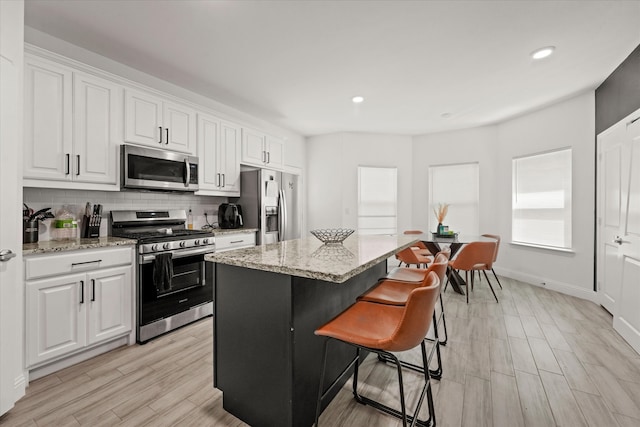 kitchen featuring appliances with stainless steel finishes, white cabinetry, a kitchen island, and light hardwood / wood-style flooring