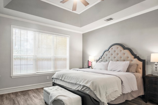 bedroom featuring ceiling fan, a tray ceiling, crown molding, and wood-type flooring