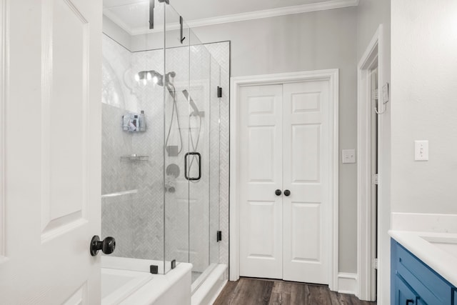 bathroom featuring vanity, wood-type flooring, a shower with shower door, and crown molding