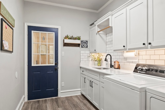 clothes washing area with cabinets, dark hardwood / wood-style floors, sink, washing machine and clothes dryer, and ornamental molding