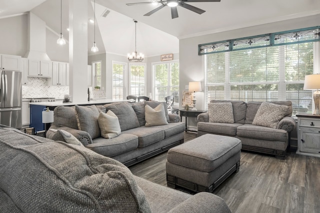 living room with ceiling fan with notable chandelier, crown molding, dark wood-type flooring, and high vaulted ceiling