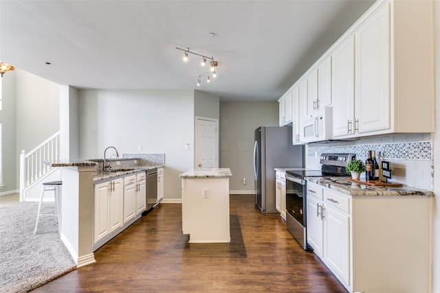 kitchen with white cabinetry, dark hardwood / wood-style floors, stainless steel appliances, and an island with sink