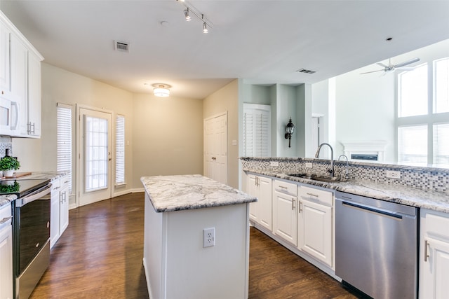 kitchen with sink, white cabinetry, a kitchen island, stainless steel appliances, and ceiling fan