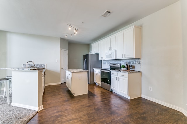 kitchen featuring appliances with stainless steel finishes, decorative backsplash, white cabinets, a kitchen island with sink, and dark hardwood / wood-style floors