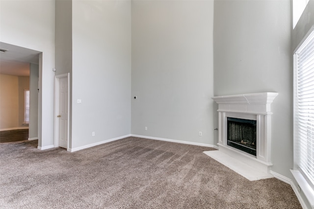 unfurnished living room with carpet floors and a towering ceiling