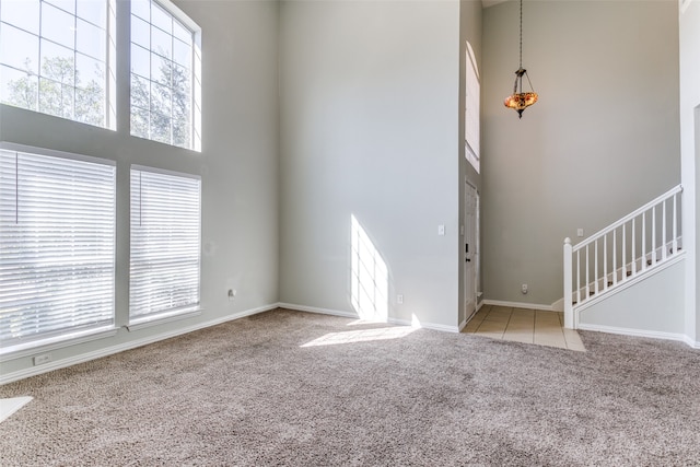 unfurnished living room with a towering ceiling and light colored carpet