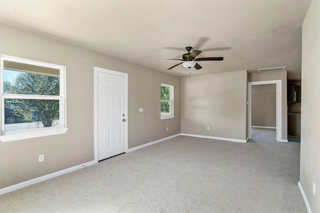 carpeted spare room featuring a wealth of natural light and ceiling fan