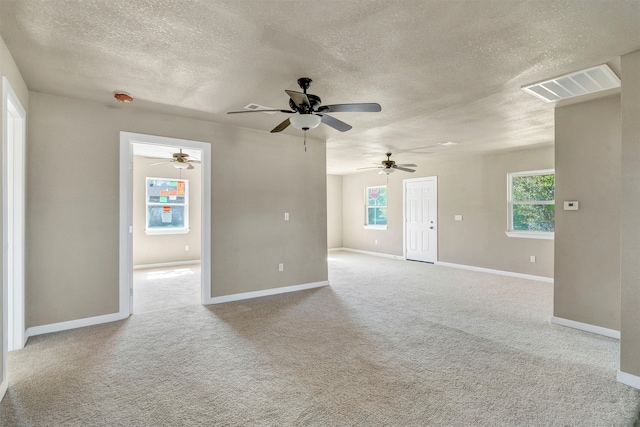 empty room with light carpet, ceiling fan, a textured ceiling, and a healthy amount of sunlight