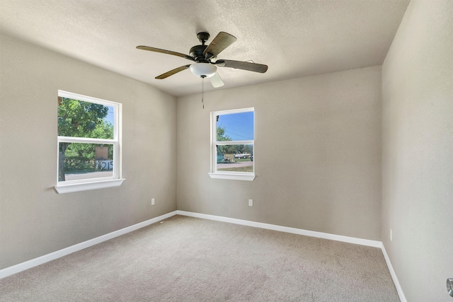 carpeted spare room with ceiling fan, a textured ceiling, and a wealth of natural light