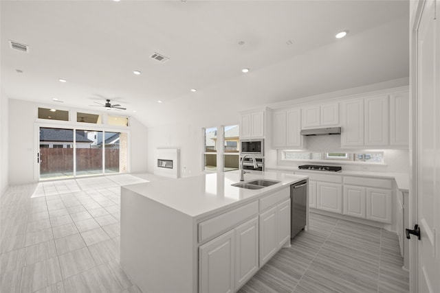 kitchen featuring vaulted ceiling, an island with sink, sink, white cabinets, and stainless steel appliances