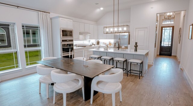 dining space featuring high vaulted ceiling, a chandelier, and light hardwood / wood-style floors