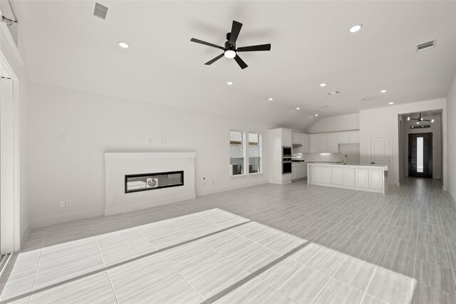 unfurnished living room featuring ceiling fan, lofted ceiling, sink, and light tile patterned floors