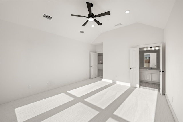 unfurnished bedroom featuring lofted ceiling, sink, ensuite bath, and ceiling fan