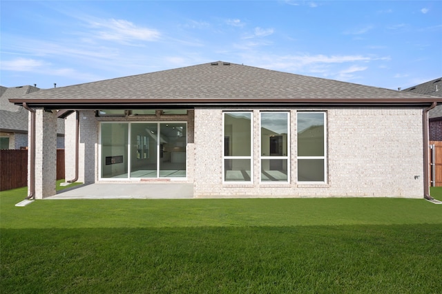 rear view of house featuring a lawn and a patio