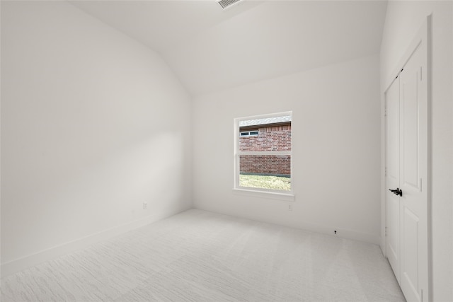 unfurnished bedroom with a closet, lofted ceiling, and light carpet