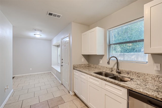 kitchen with stainless steel dishwasher, white cabinetry, sink, and light stone counters