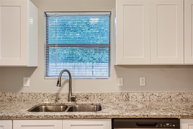 kitchen with light stone counters, dishwasher, sink, and white cabinetry