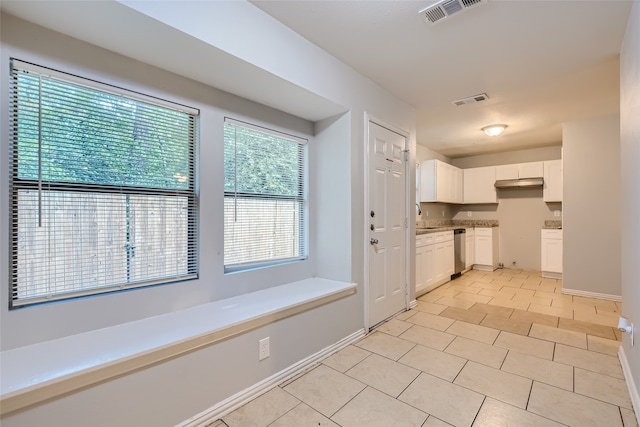 kitchen with light tile patterned flooring, white cabinetry, dishwasher, and sink