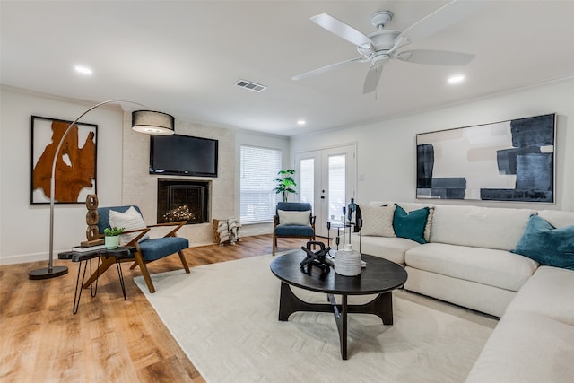 living room with a fireplace, ornamental molding, hardwood / wood-style flooring, and ceiling fan