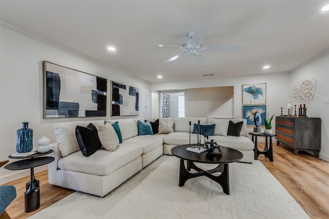 living room featuring ornamental molding, light wood-type flooring, and ceiling fan