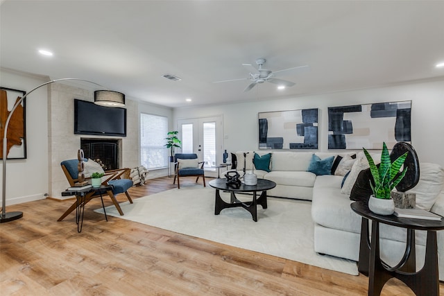 living room featuring ceiling fan, crown molding, a fireplace, french doors, and hardwood / wood-style flooring