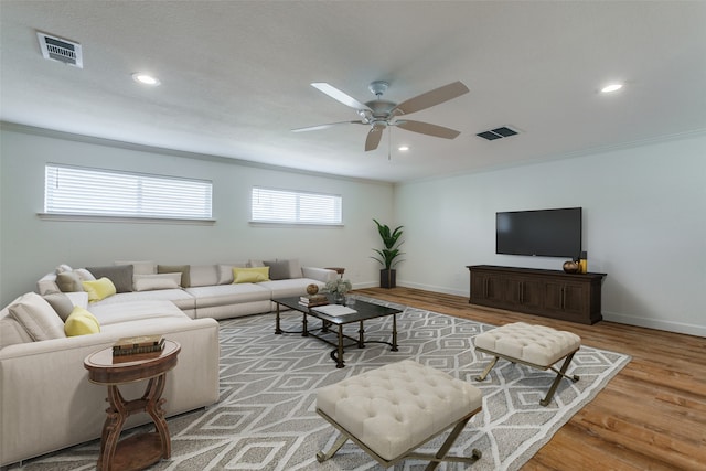 living room featuring ceiling fan, plenty of natural light, light hardwood / wood-style floors, and crown molding