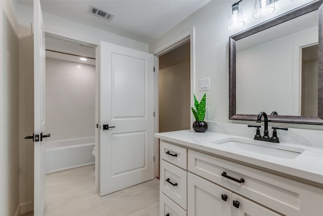 full bathroom featuring tiled shower / bath, vanity, and toilet