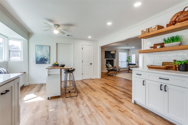 kitchen featuring white cabinets, light wood-type flooring, and a kitchen bar