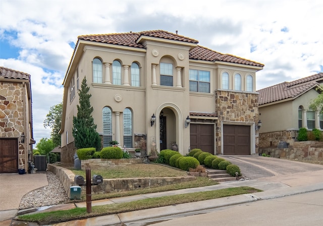 mediterranean / spanish-style home with a garage and central air condition unit