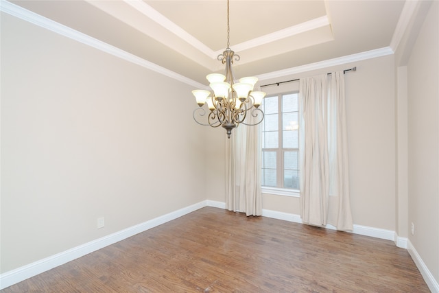 unfurnished room featuring hardwood / wood-style floors, crown molding, an inviting chandelier, and a tray ceiling