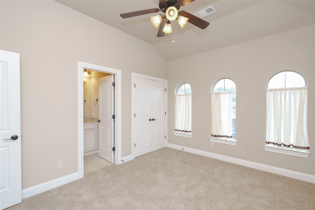 unfurnished bedroom featuring lofted ceiling, ceiling fan, light colored carpet, and ensuite bathroom