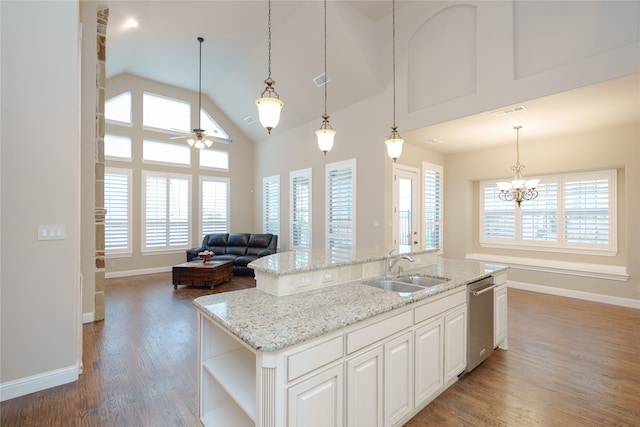 kitchen featuring dark wood-type flooring, white cabinets, ceiling fan with notable chandelier, a kitchen island with sink, and sink