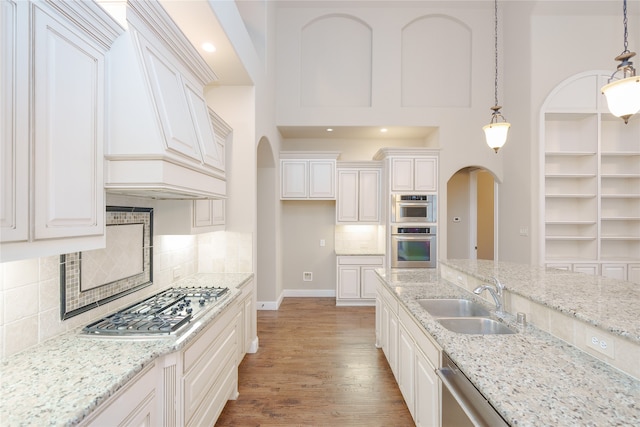 kitchen with white cabinets, sink, decorative light fixtures, hardwood / wood-style flooring, and appliances with stainless steel finishes