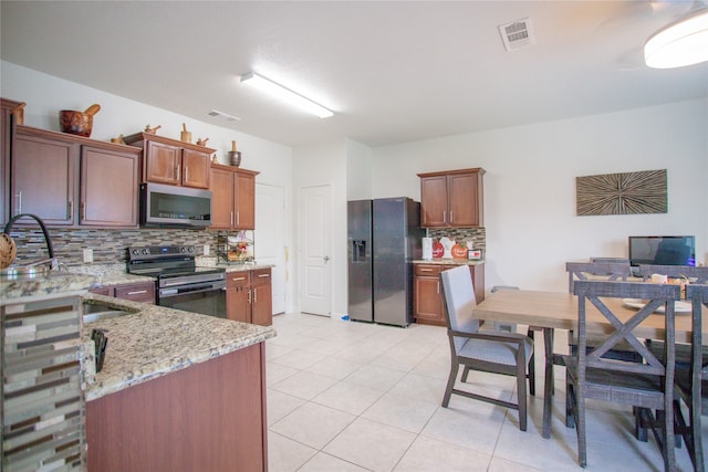 kitchen featuring light stone countertops, decorative backsplash, appliances with stainless steel finishes, and light tile patterned floors