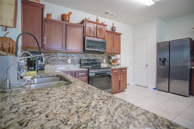 kitchen featuring tasteful backsplash, sink, appliances with stainless steel finishes, light tile patterned floors, and light stone countertops