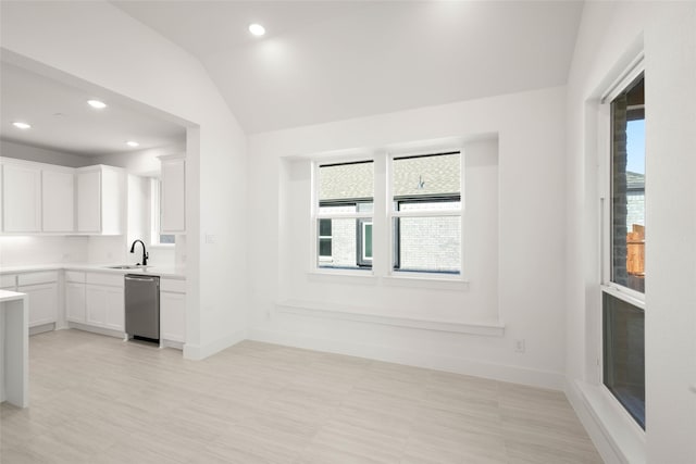 kitchen with white cabinetry, stainless steel dishwasher, a healthy amount of sunlight, and vaulted ceiling