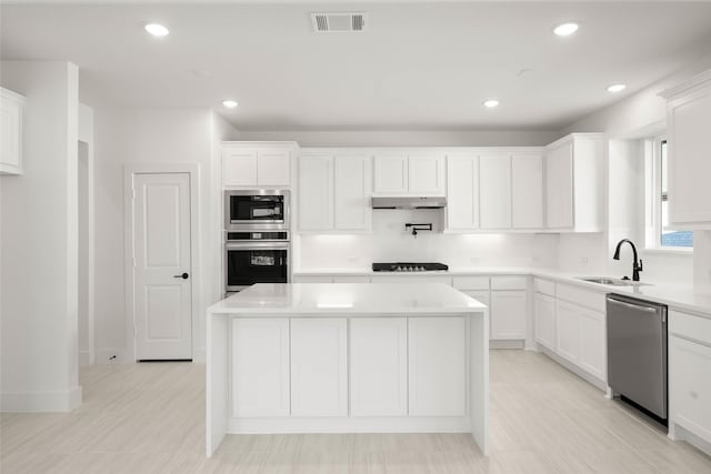 kitchen featuring white cabinetry, stainless steel appliances, sink, and a kitchen island