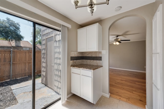 kitchen with ceiling fan, light hardwood / wood-style flooring, white cabinetry, dark stone countertops, and decorative backsplash