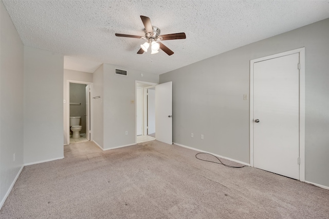 unfurnished bedroom featuring ceiling fan, a textured ceiling, light carpet, and ensuite bath