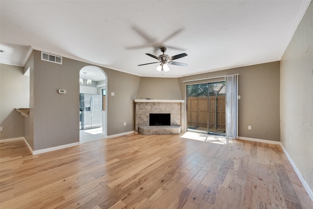 unfurnished living room featuring light hardwood / wood-style floors, ornamental molding, ceiling fan, and a brick fireplace