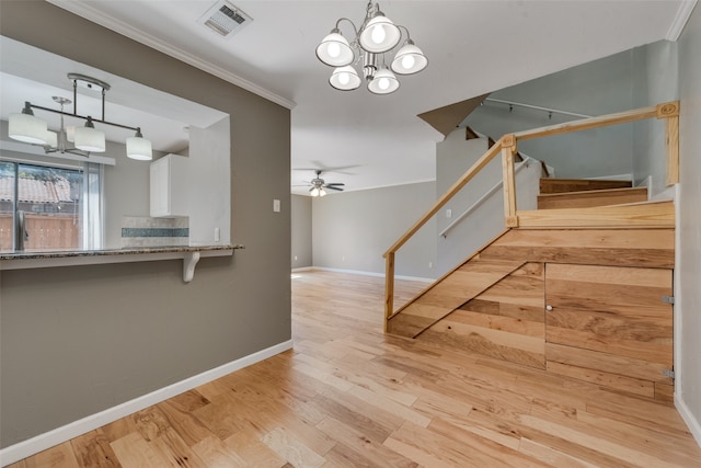 interior space with ceiling fan with notable chandelier, crown molding, and hardwood / wood-style floors