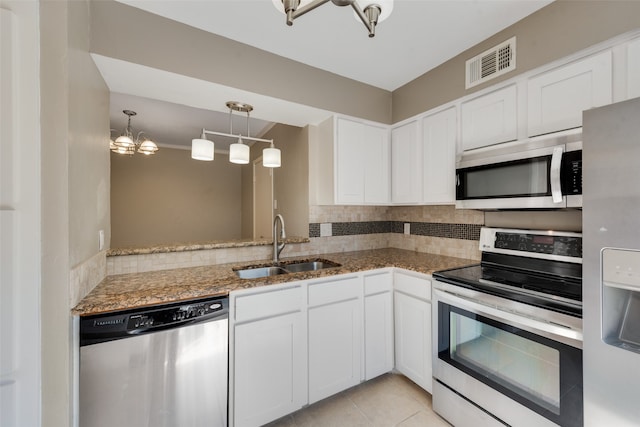 kitchen featuring appliances with stainless steel finishes, white cabinets, pendant lighting, sink, and a notable chandelier