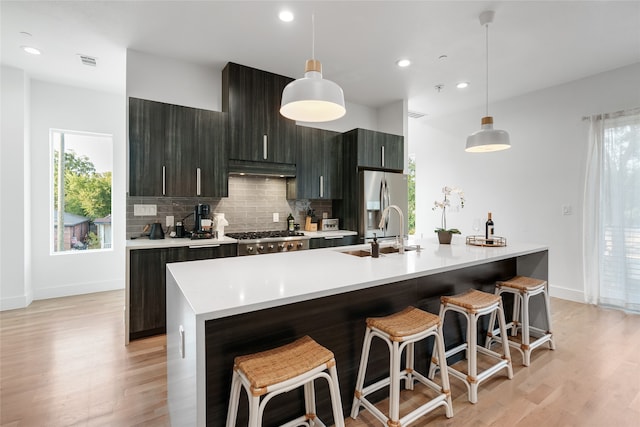 kitchen featuring pendant lighting, an island with sink, plenty of natural light, and sink